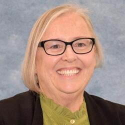 Rosemary Tyrrell, Director of the Office of Faculty Development at UC Riverside, wearing a green shirt with black cardigan smiling for headshot