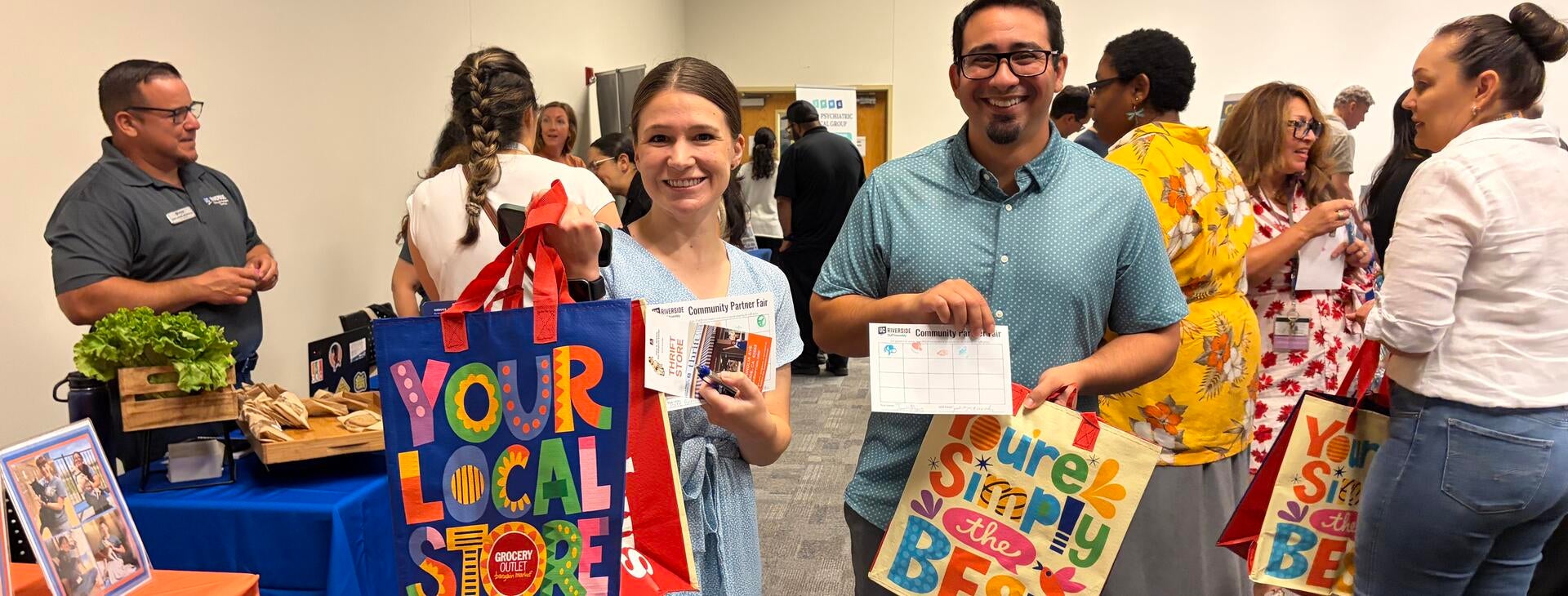 UCR staff showing off their tote bags and stamp rally card.