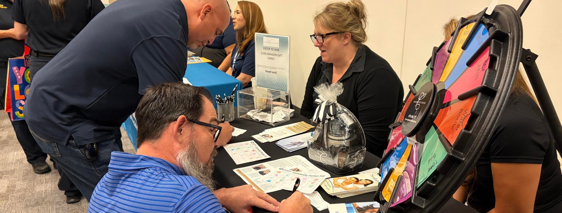 Community Partner Fair attendees filling out a form at a vendor table.