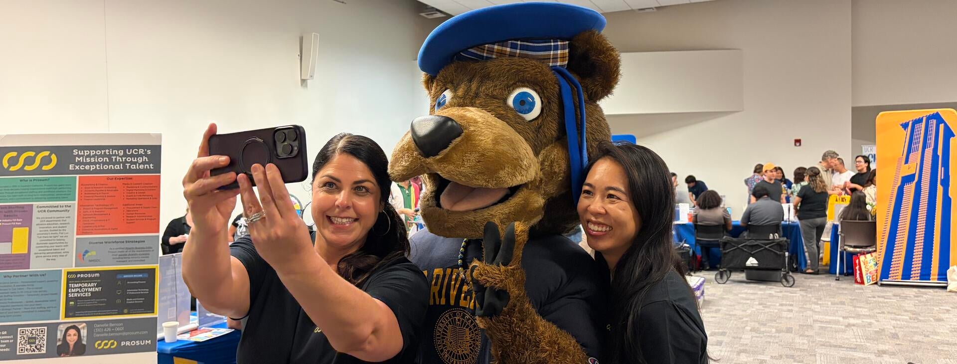Community Partner Fair vendors take a selfie with Scotty Bear.